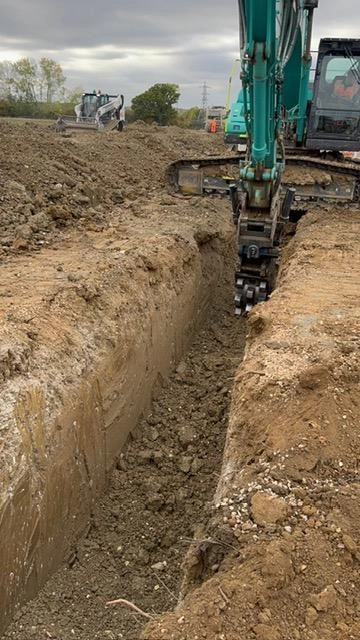 Excavator-mounted compactor working in the drainage trench